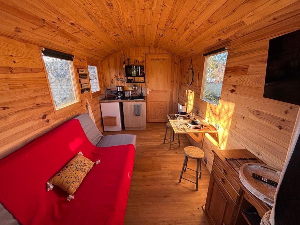 Una sala de estar con un sofá rojo en una cabaña. en La Roulotte Saintaise, en Saintes