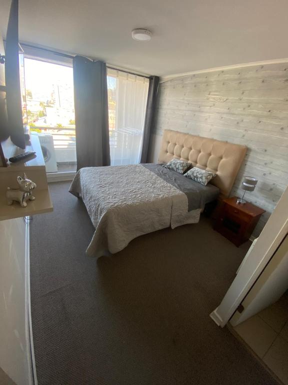 a bedroom with a large bed and a large window at Bello Dpto central a pasos de la Quinta Vergara, Mall, Plaza de Viña, con estacionamiento, ideal para recorrer la ciudad caminando relajado in Viña del Mar