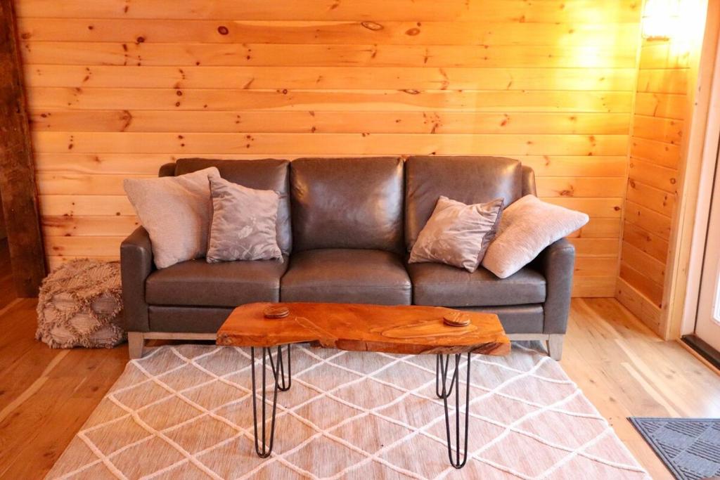un divano in pelle in un soggiorno con una parete in legno di Stonebrook Hollow Cabin a Tidwell