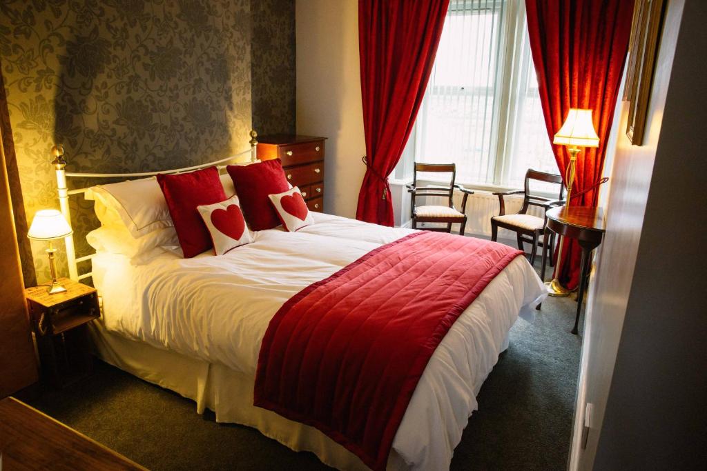 Cette chambre comprend un grand lit avec des oreillers rouges. dans l'établissement Coalminer's Cottage, à Gateshead