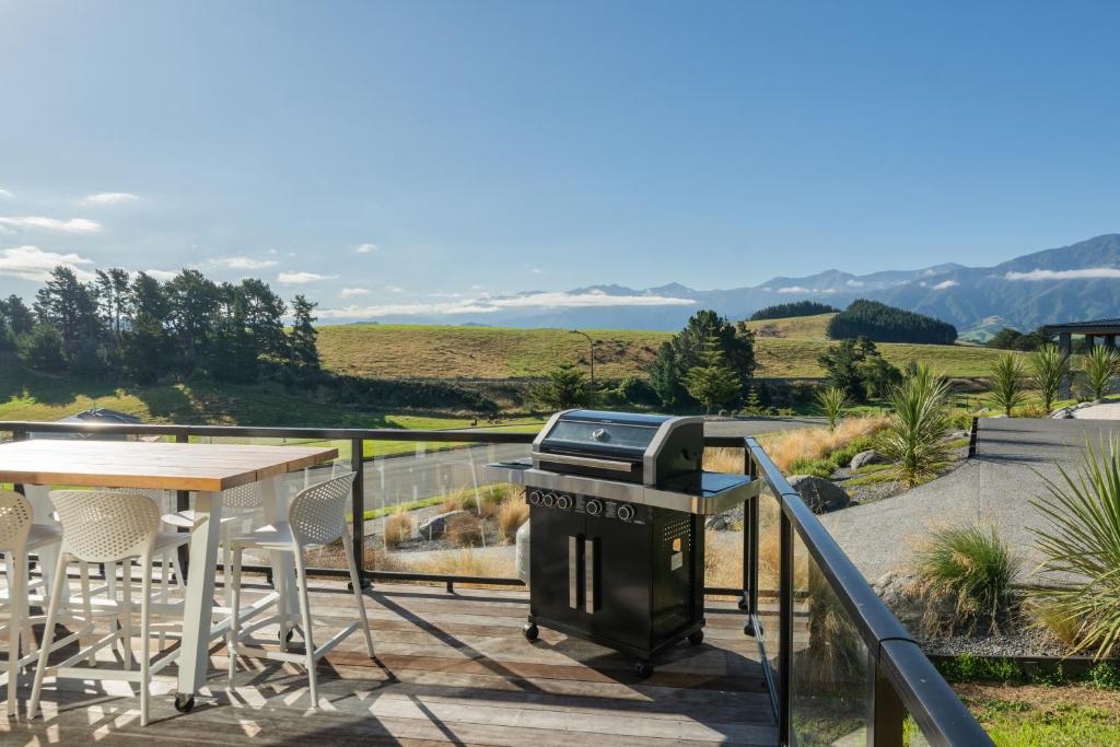 a grill on a balcony with a table and chairs at Stunning Views, Contemporary, Escape - KK24113 in Kaikoura