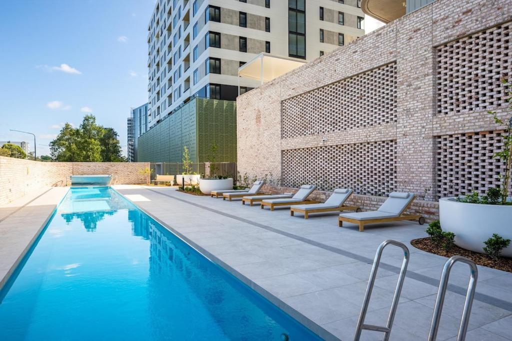 a swimming pool with lounge chairs next to a building at Modern 2 Bedroom Apartment in Phillip with Parking in Phillip