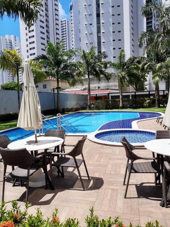 a patio with tables and chairs next to a swimming pool at Flat Rosarinho II - Confortável e Super Completo in Recife