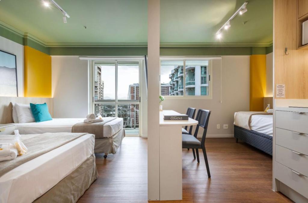 a hotel room with two beds and a desk at Flat na Barra da Tijuca-G 1408-3 in Rio de Janeiro