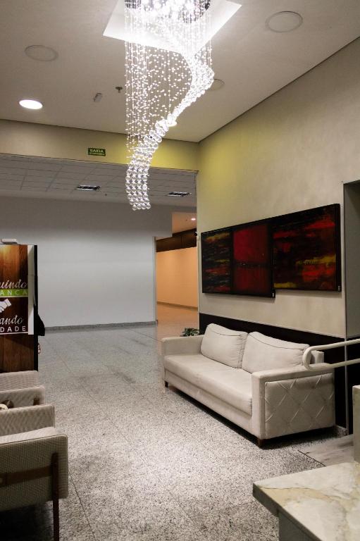 a living room with a couch and a chandelier at Hotel Aero Sleep Campinas in Campinas