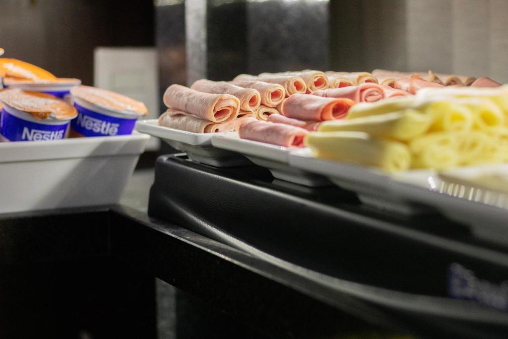 a bunch of hot dogs and pasta on trays at Hotel Aero Sleep Campinas in Campinas