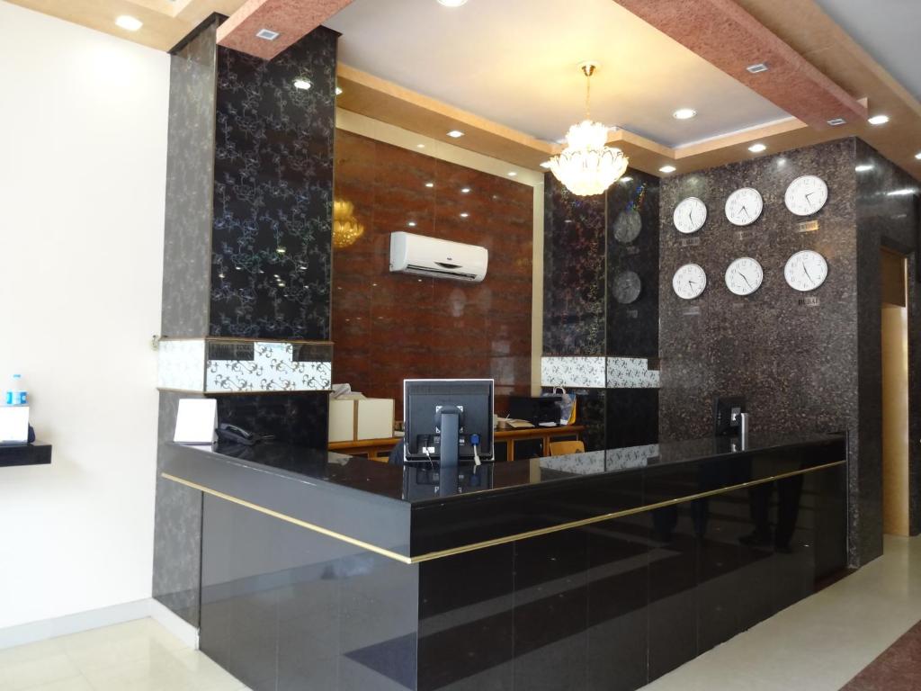 a lobby with a black counter with clocks on the wall at Hotel Sky Towers in Karachi