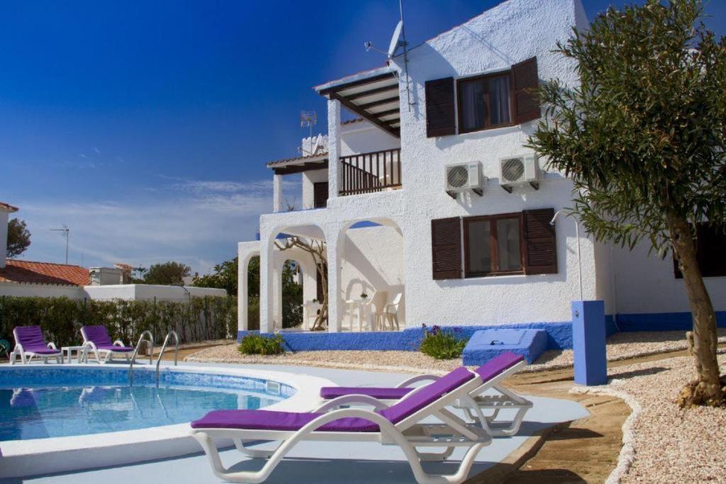 a villa with a swimming pool in front of a house at Apartamentos Blue Beach by Escape Home in Cala en Forcat