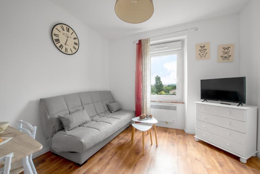 un salon avec un canapé et une horloge au mur dans l'établissement Aurora - T1 - 25, à Carcassonne