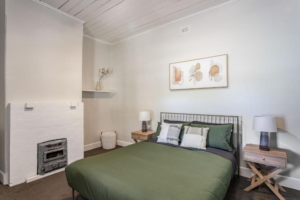 - une chambre avec un lit vert et une cheminée dans l'établissement Maranka Homestead, à Waikerie