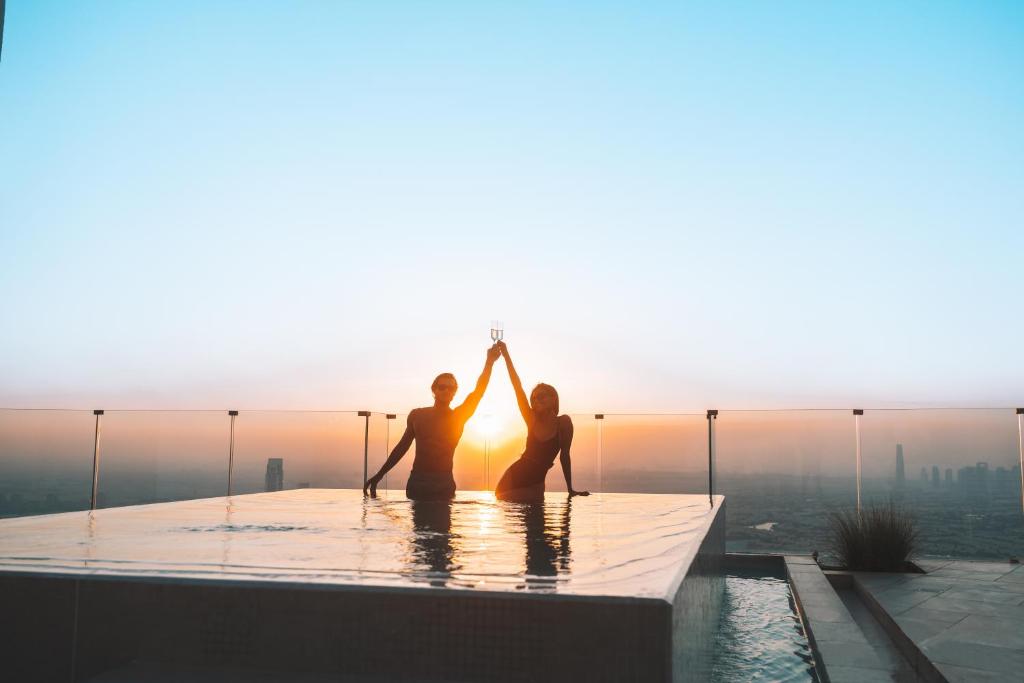 two people sitting in the infinity pool at the shard with the sunset at FIVE Jumeirah Village in Dubai