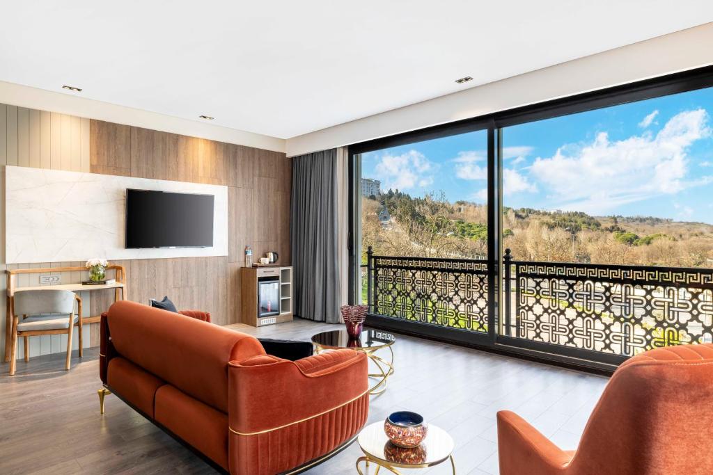 Elle comprend un salon doté d'un mobilier orange et d'une grande fenêtre. dans l'établissement Ezkar Bathonea Art İstanbul Hotel, à Avcılar