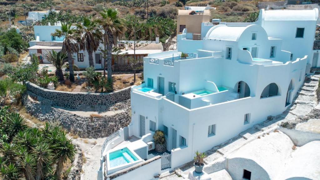 an aerial view of a white house with palm trees at White Cave Villas in Oia