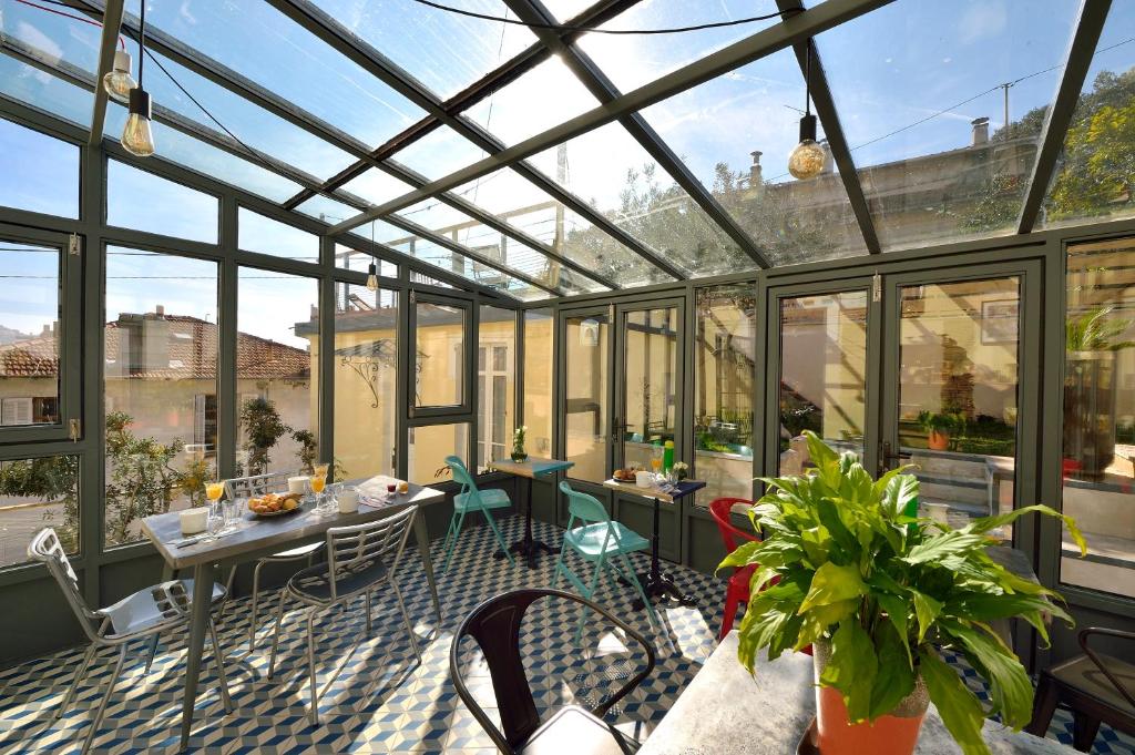 un giardino d'inverno in vetro con tavolo e sedie di B&B Villa Du Roc Fleuri a Cannes