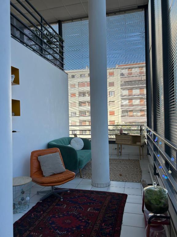 - un salon avec un canapé vert et de grandes fenêtres dans l'établissement Un duplex à PARIS DAUMESNIL, à Paris