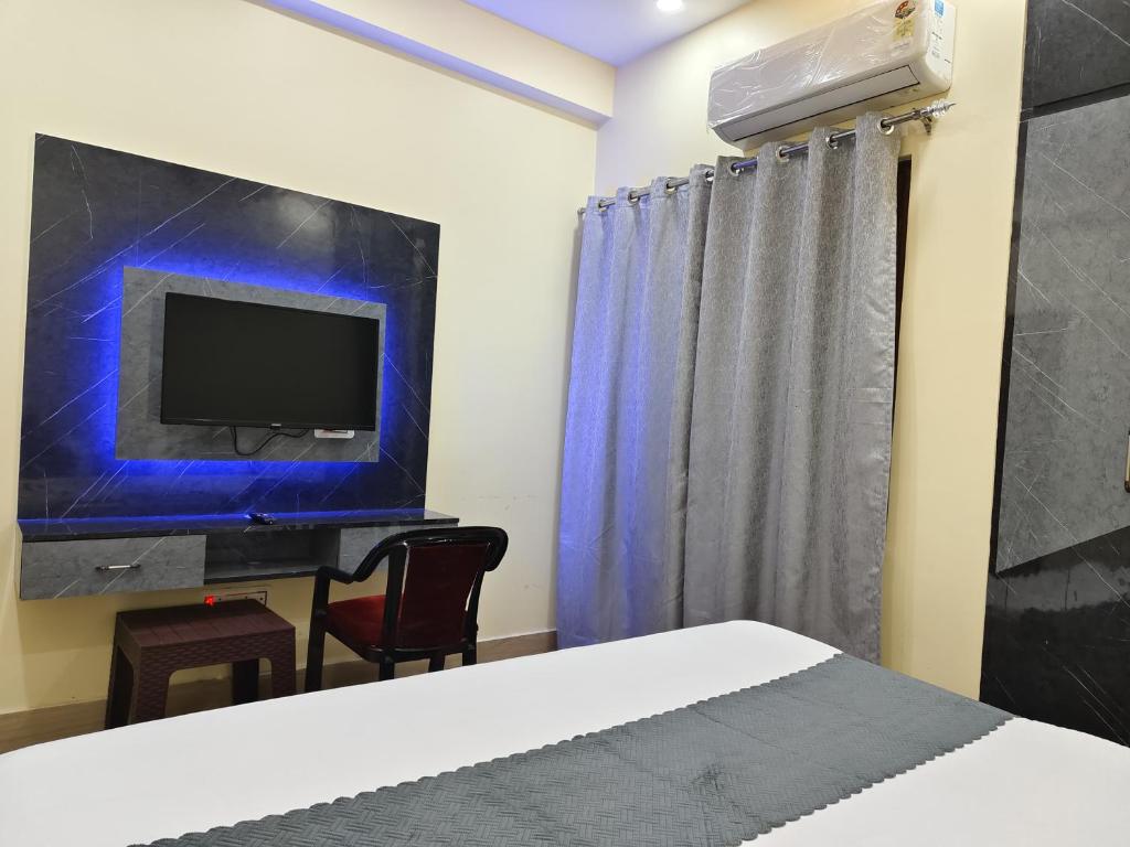 Un dormitorio con una cama, un televisor y una silla. en Kartikey Home Stay, en Varanasi