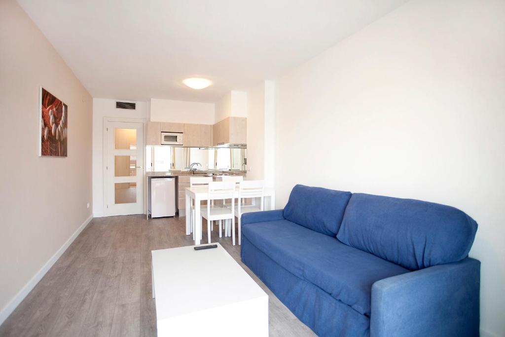 sala de estar con sofá azul y mesa en Apartamentos Port Eugeni, en Cambrils