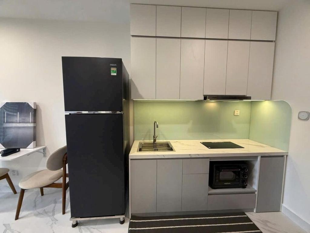 a kitchen with a black refrigerator and a sink at Căn hộ Beverly Vinhomes grand park Q9 - An Trú Homestay in Gò Công