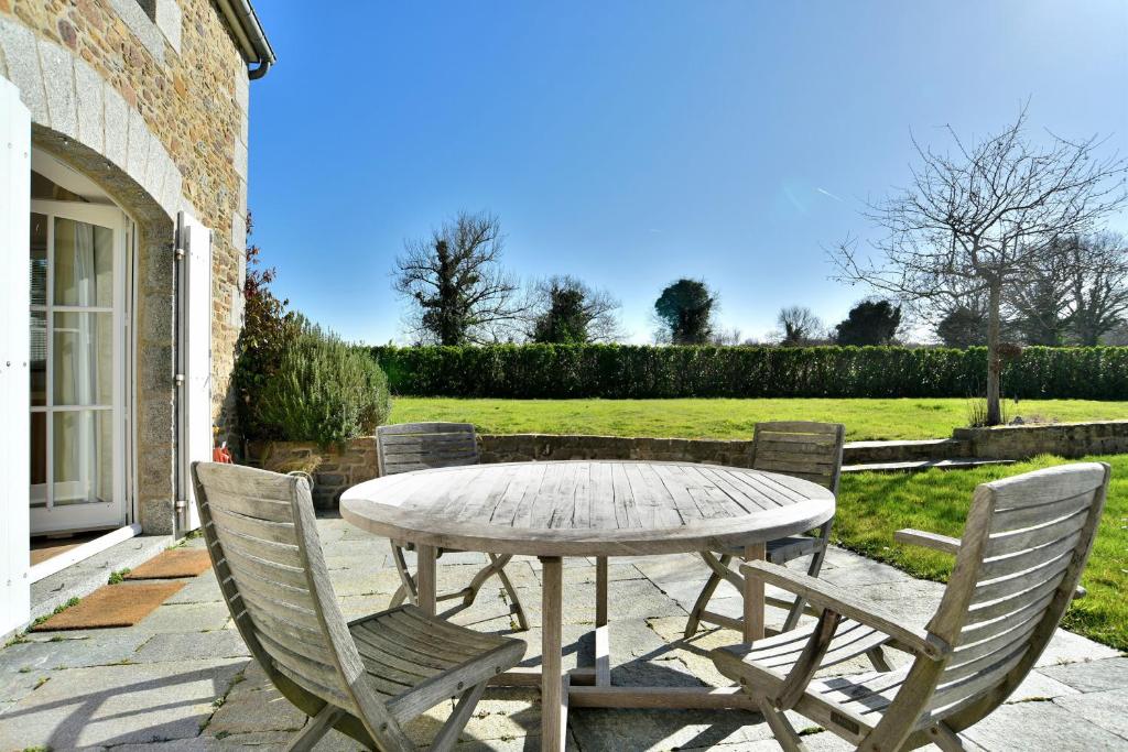 une table et des chaises en bois sur une terrasse dans l'établissement Le Verger - Charmante maison avec jardin, à Saint-Lunaire