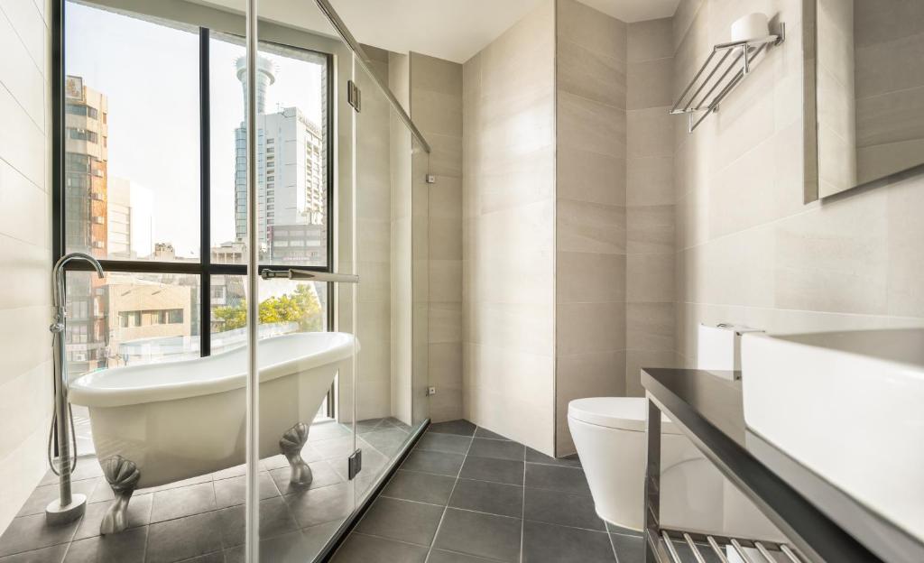 a bathroom with a tub and a toilet and a window at 凝萃文旅 台中車站店 NCH-Business Hotel in Taichung