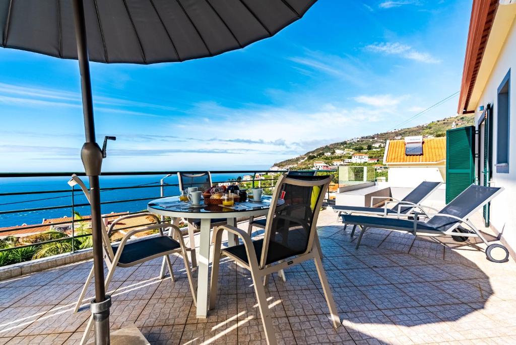 a patio with a table and chairs and an umbrella at Casa Flora, 2 quartos,vista mar in Arco da Calheta