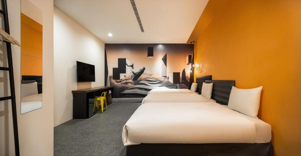 a row of beds in a room with orange walls at 凝萃文旅 台中車站店 NCH-Business Hotel in Taichung