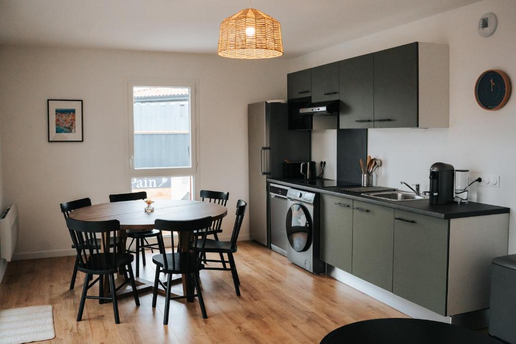 une cuisine et une salle à manger avec une table et des chaises dans l'établissement Résidence Boho Lacanau, à Lacanau