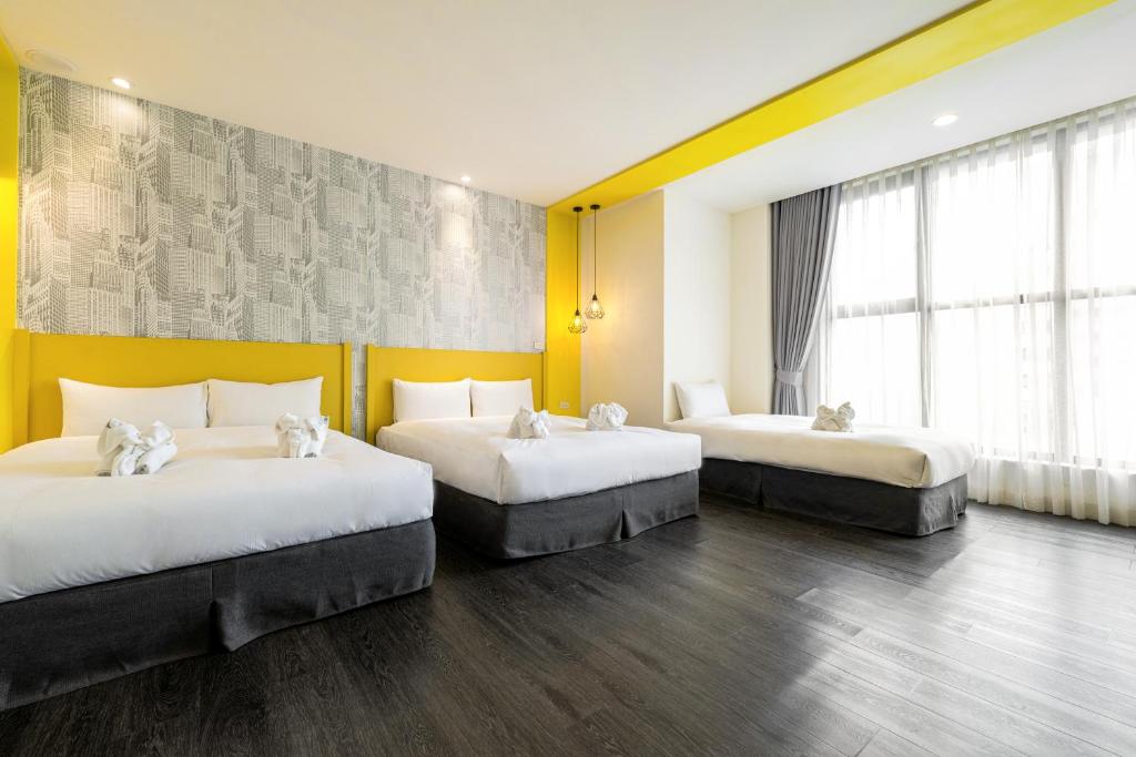 two beds in a room with yellow walls at 凝萃文旅 台中車站店 NCH-Business Hotel in Taichung