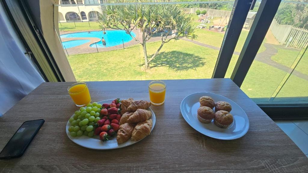 two plates of food on a table with fruit and juice at Cabanas Del Mar 32 in Kingsburgh