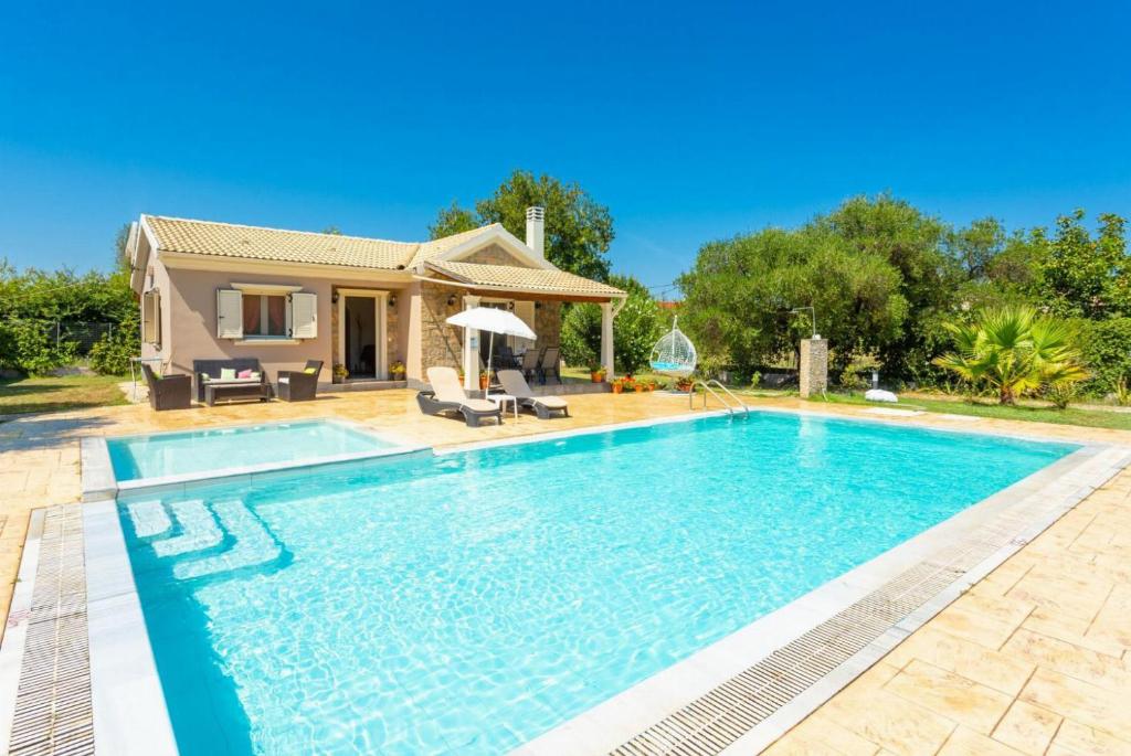 a swimming pool in front of a house at Villa Popi in Roda