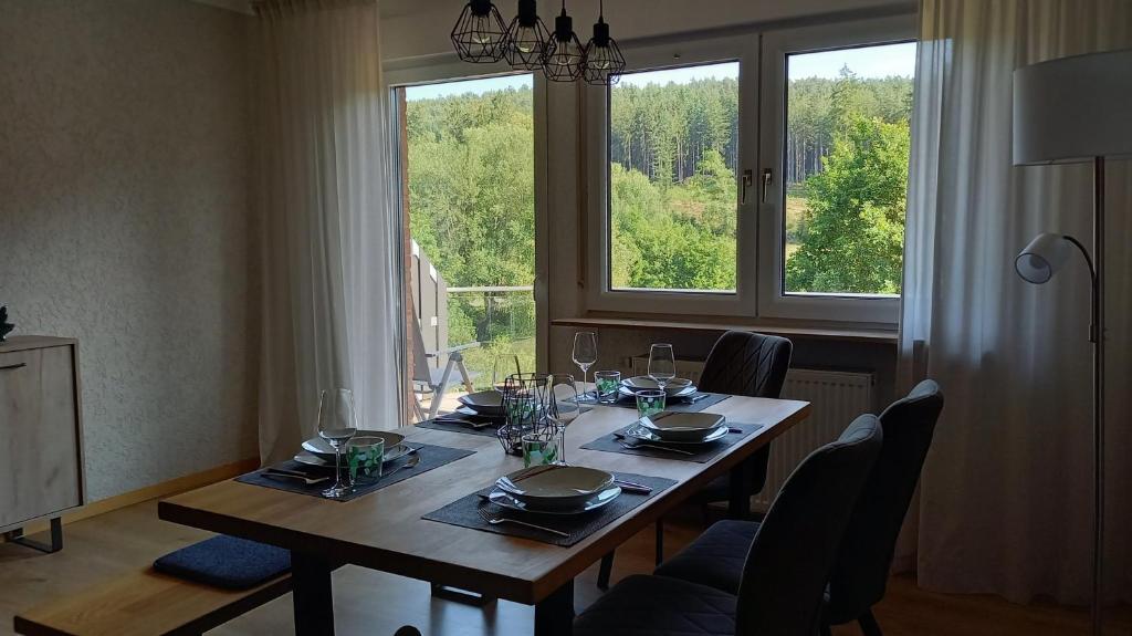 a dining room table with chairs and a large window at Ferienwohnung Mossauer Hoehe in Mossautal