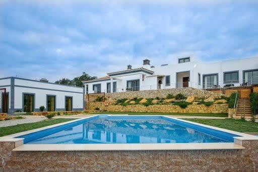 a house with a swimming pool in front of a house at Villa Areias II - Beautiful landscape garden in Estói