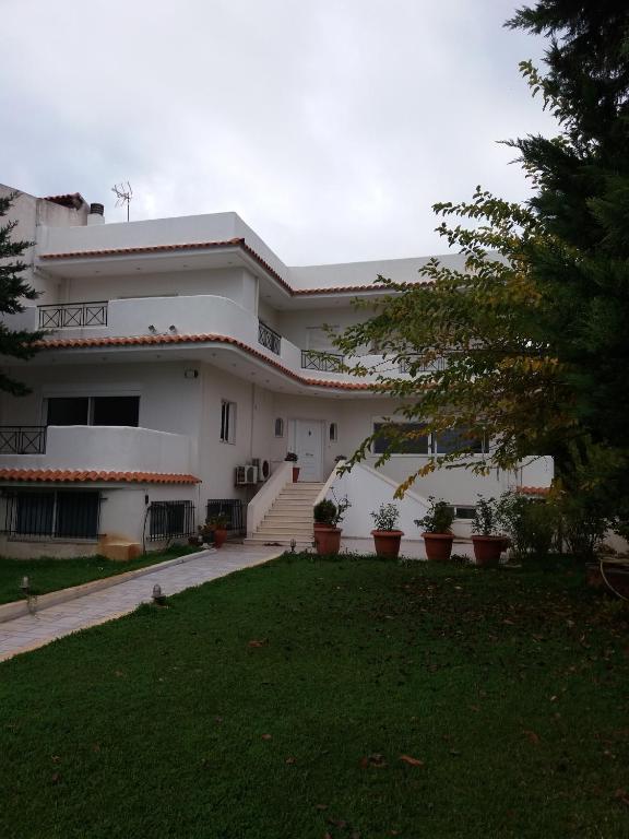 a large white house with a lawn in front of it at Beach House Villa in Nea Makri