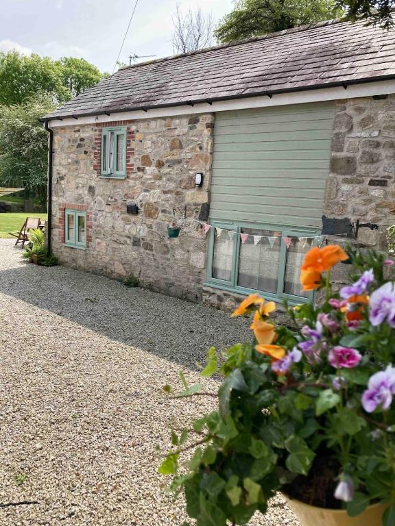 a stone house with flowers in front of it at Blaise Cottage Cornwall in St Austell