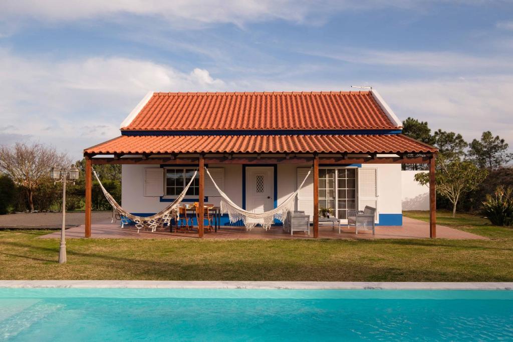 a house with an orange roof next to a pool at Casa do Arrozal Comporta in Comporta