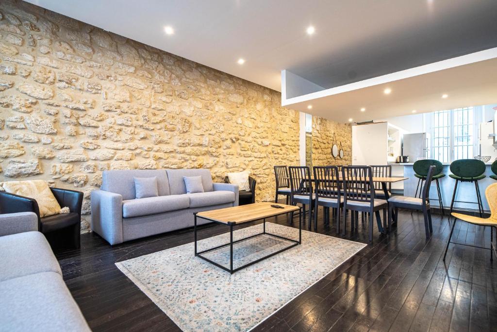 un salon avec des canapés et un mur en pierre dans l'établissement CIA - Réaumur Étienne Marcel 8P, à Paris
