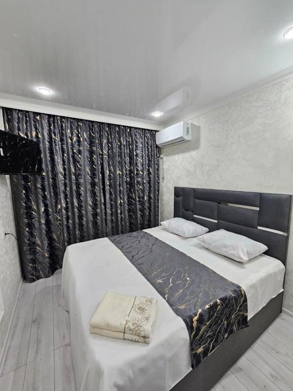 a bedroom with a large bed with a black curtain at Апарт Отель MaRi in Shymkent