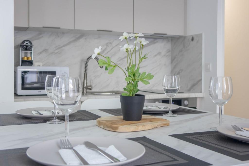 - une table avec des verres à vin et un vase avec des fleurs blanches dans l'établissement Le Cosy Place - charmant T2 avec Parking - Orléans Hyper Centre, à Orléans