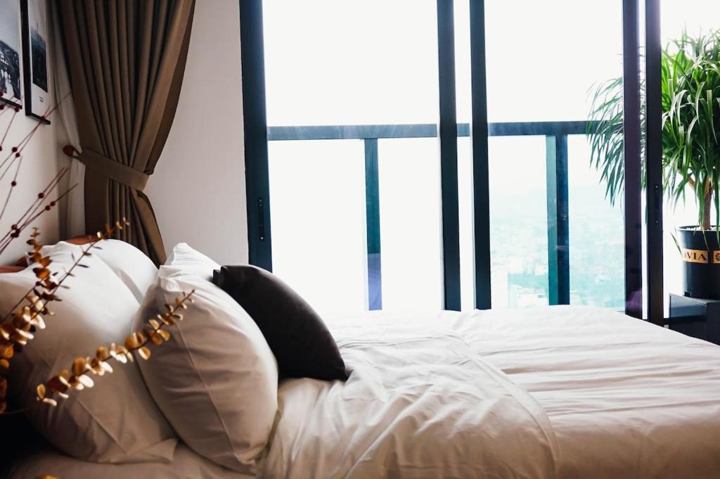 a bed with white sheets and pillows in front of a window at Luxury Apartment in Hai Phong near CatBi international Aport in Ðông Khê