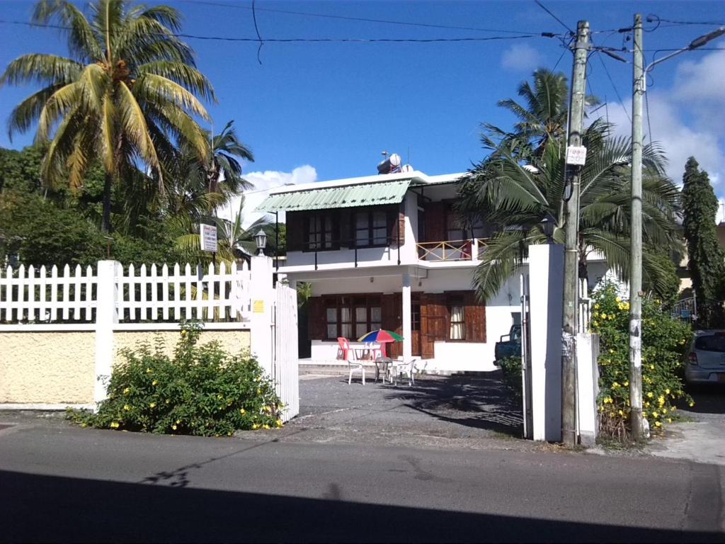 een wit huis met een wit hek en een palmboom bij Auberge Etiennette in Trou dʼ Eau Douce