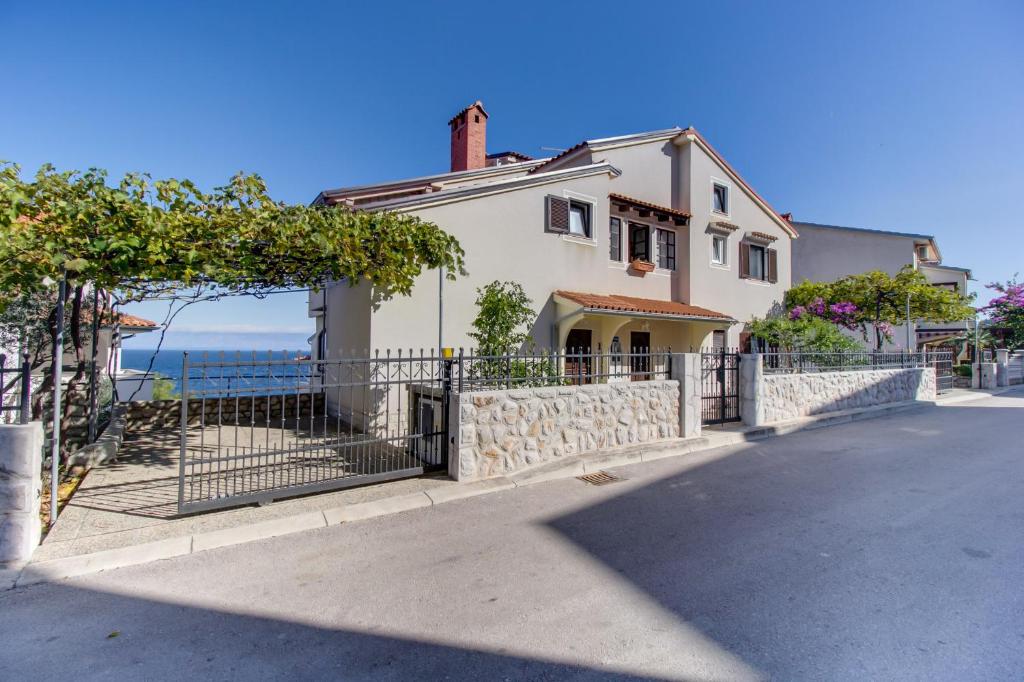 ein Haus mit einem Zaun vor dem Meer in der Unterkunft Apartments Anci in Mali Lošinj