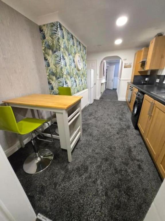 a kitchen with a desk and green chairs in a room at Levy Nook House 1 bed apartment 5 minute walk to Stockton town centre & Free Parking in Stockton-on-Tees