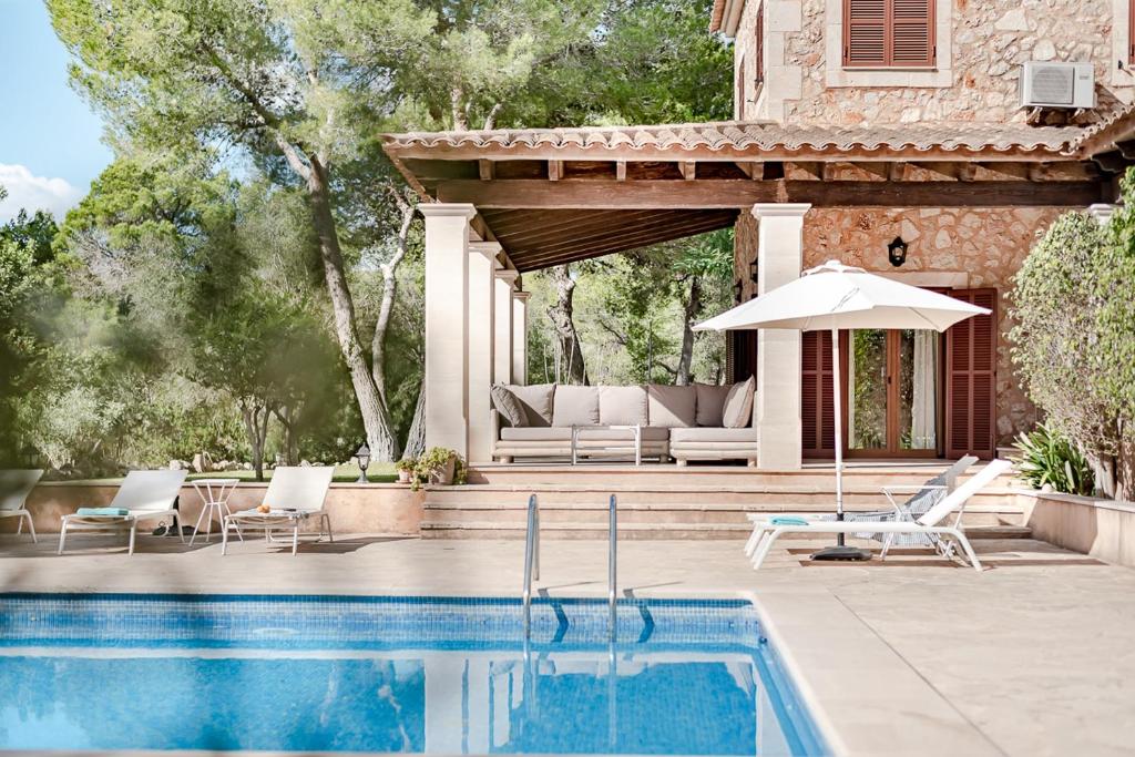 a patio with a pool and a couch and an umbrella at Es Puig De Portocolom in Cala Murada