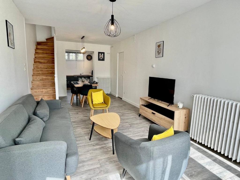 un salon avec un canapé, une télévision et une table dans l'établissement Escapade à Royan - A 5min de la gare jardin, à Royan