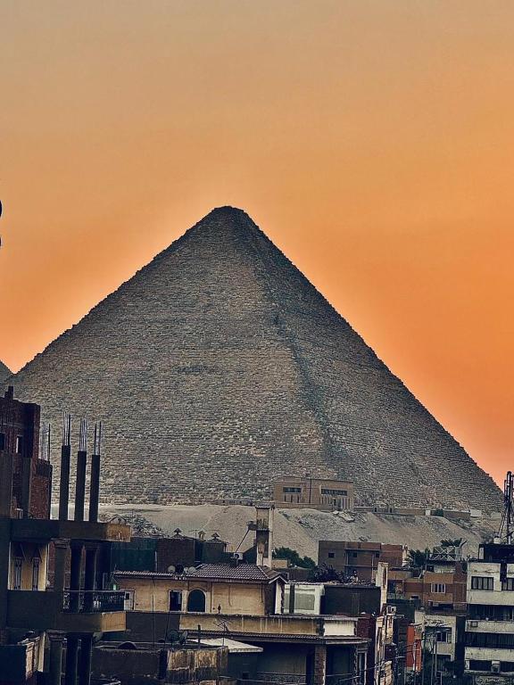 a pyramid in the background of a city at Khufu Pyramids View Inn in Cairo
