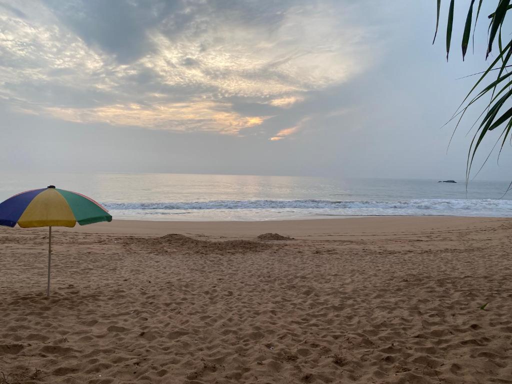 a blue and yellow umbrella on a sandy beach at Coastal Heaven in Bentota