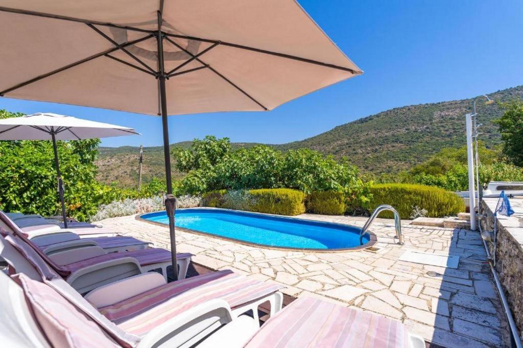 una villa con piscina y sombrilla en Three Bedroom Holiday Home with Pool, en Molunat