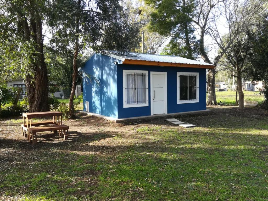 a blue and white shed in a park with a bench at Los Eucaliptos Chascomús in Chascomús