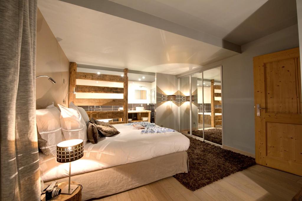 a bedroom with a large white bed and a mirror at Chalet Christine in Talloires