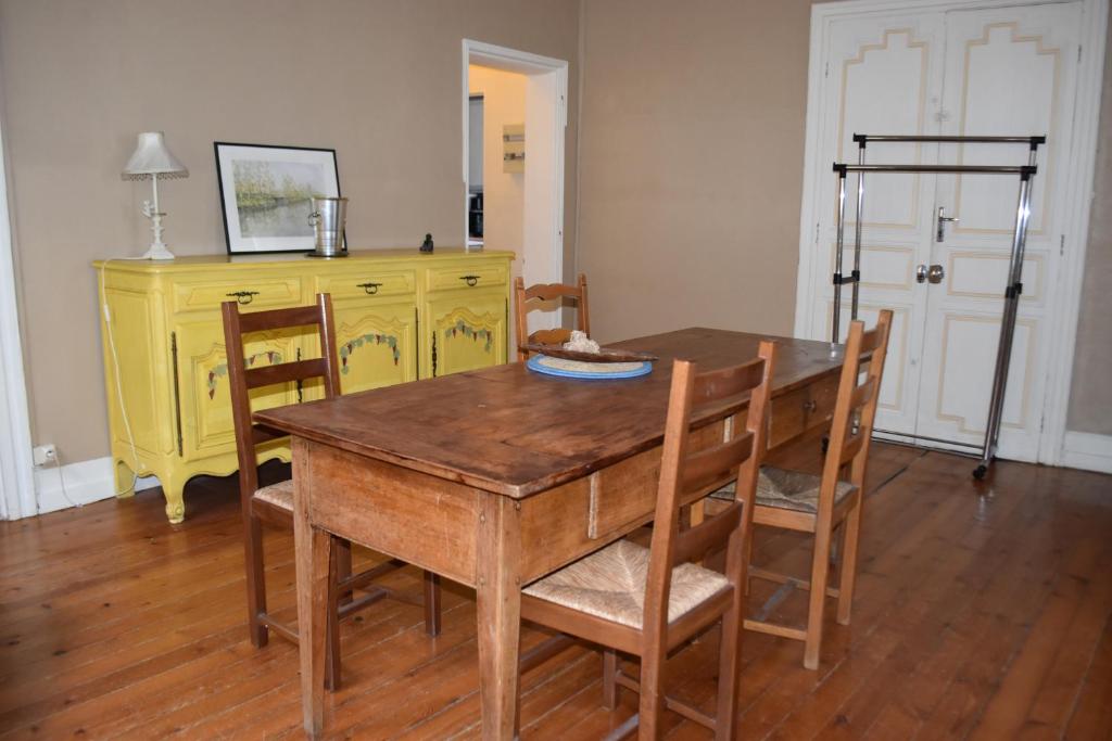 une salle à manger avec une table en bois et une commode jaune dans l'établissement Appartement de caractère, à Bourg